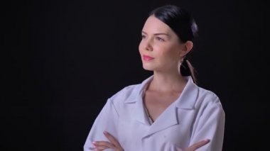 Kendine güvenen genç güzel kadın doktor siyah arka plan üzerine izole kamera ayakta çapraz el ile bakıyor