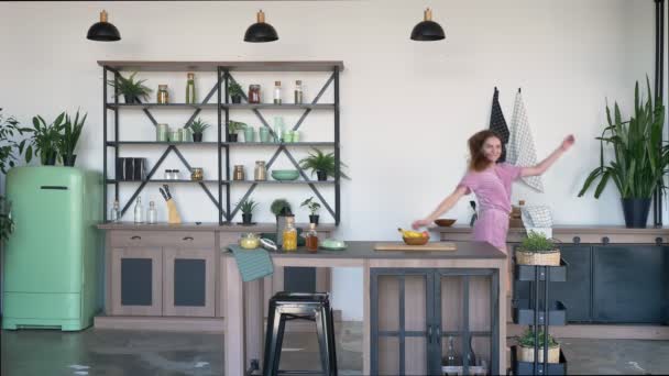 Joven hermosa mujer bailando en la cocina y tomando plátano, alegre y alegre hembra en casa durante la mañana — Vídeos de Stock
