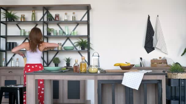 Jengibre mujer feliz bailando y cantando en stapula, fondo de cocina moderna, alegre y alegre mujer con pantalones de pijama — Vídeos de Stock