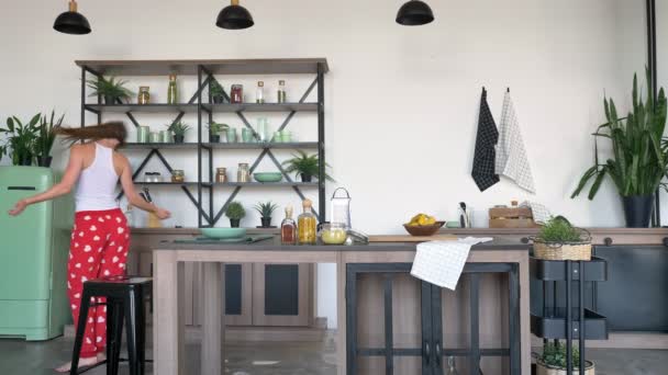 Hermosa esposa encantadora bailando movimientos divertidos, esperando marido y levantando las manos, cocina moderna en el fondo — Vídeo de stock