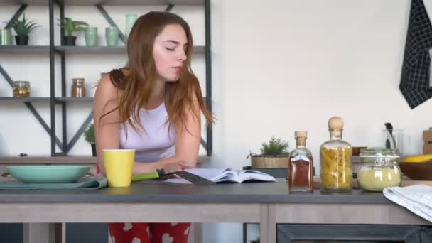 Vicces ginger nő kulináris könyvet olvas, és a modern konyha során a főzési folyamat, a reggeli tánc — Stock videók