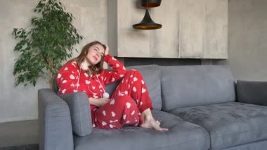 Kanepede oturan ve kulaklık, holding telefon, modern oturma odası arka planda müzik büyüleyici genç kadın