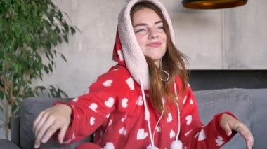 Hearts oyununda kırmızı pijama giymiş ve kulaklık aracılığıyla müzik, dans ve kapalı koltukta oturan komik neşeli kadın