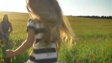 Küçük kız annesine çalıştıran ve onu mutlu ve neşeli, gülümseyen kucaklayan uzun sarı saçlı güzel buğday alan günbatımı sırasında