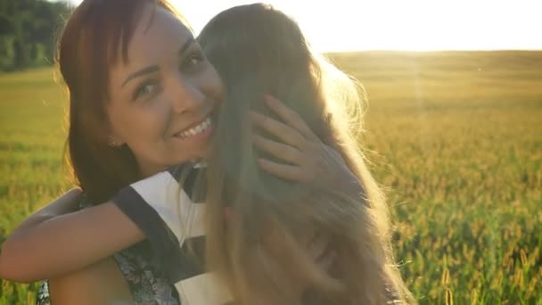 Kleine Tochter umarmt glücklich charmante Mutter, lächelnd, Weizen- oder Roggenfeld bei Sonnenuntergang im Hintergrund, fröhlich und fröhlich — Stockvideo