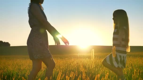 Joven madre y su hijita se van el uno al otro y se abrazan, observan la puesta de sol en el fondo, hermosa vista del trigo o el campo de centeno — Vídeos de Stock