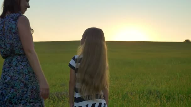 Achteraanzicht van de moeder afkomstig en haar kleine blonde dochter, staande in het midden van tarwe of rogge veld knuffelen — Stockvideo