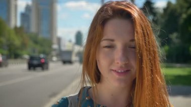 Kamera road, güzel kadın genç yakınında kentsel sokakta duran, gülümseyen sevimli zencefil genç kadın portresi