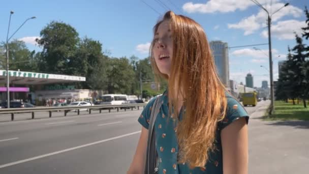 Jeune femme gingembre charmante avec sac grêle taxi, rue urbaine avec route en arrière-plan, cabine d'appel féminine — Video