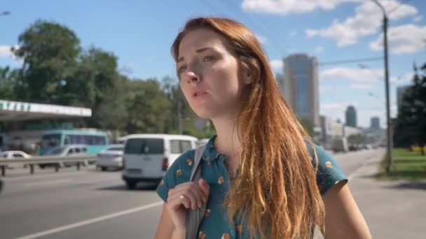 Betrokken gember jonge vrouw te wachten voor een taxi en staande op stedelijke straat in de buurt road, benadrukt en bezet van emoties — Stockvideo