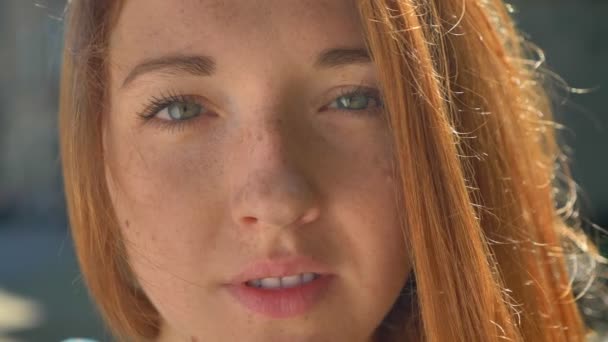Beautiful young ginger teenager with blue eyes looking at camera, happy charming female smiling — Stock Video