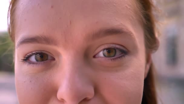 Fermer les images de belles jeunes femmes roux yeux regardant la caméra, à l'extérieur, de jour — Video