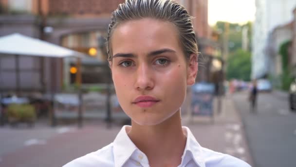 Preciosa mujer moderna está caminando en la ciudad y mirando a la cámara en el día, concepto urbano, fondo borroso — Vídeo de stock