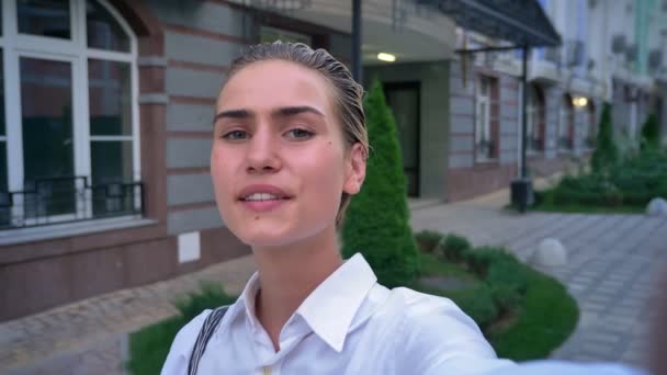 Jovem mulher moderna está de pé na rua, segurando câmera, fazendo selfie, conceito de comunicação — Vídeo de Stock