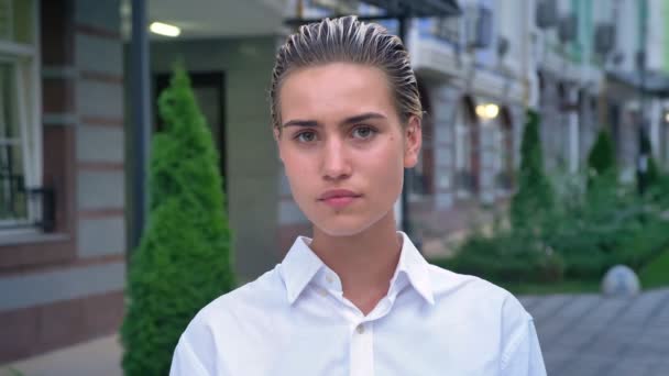 Sad modern woman is standing on street and watching at camera in evening, urban concept — Stock Video