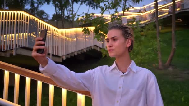 Mulher moderna está em pé na escada, fazendo selfie no smartphone à noite, conceito de comunicação — Vídeo de Stock