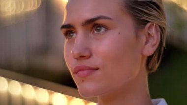 İlham genç modern kadın akşam, kameraya izliyor ışıklar açık arka plan bulanık gülümseyen,