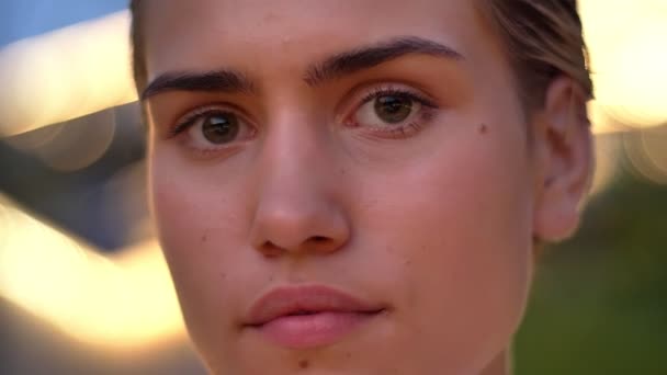 Tvář mladé moderní ženy se dívá na kameru v večer, rozmazané světla na pozadí — Stock video