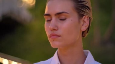 Üzgün modern kadın kameraya akşam arka plan bulanık ışıkları içinde izliyor