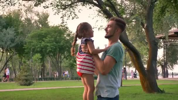 Красивий батько кидає в повітря свою маленьку доньку, сімейну концепцію — стокове відео