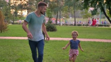 Genç aile yaz, kızı ve babası kavramı oynarken annesine çalıştırmak Park'ta oturuyor.