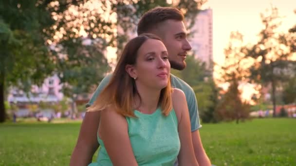 Mladá rodina sedí na koberci v parku v létě, Dcera běží kolem rodičů, relax koncept — Stock video