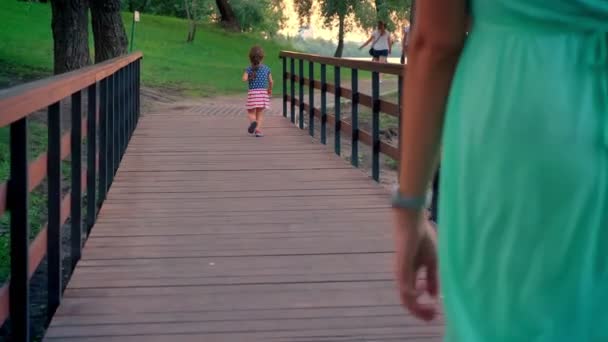 Silhouet van klein meisje loopt langs het pad in het park in de zomer, zonsondergang, dat haar moeder volgt haar — Stockvideo