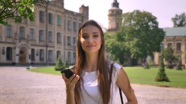 Seksi Bayan gündüz, watchimg sonra fotoğraf makinesi smartphone içinde parkta duruyor