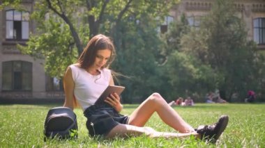 Seksi Bayan Park çimenlerin üzerinde gündüz de oturmuş, tablet, kavram, iletişim kavramı relax izlerken