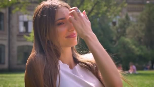 Sexy dama está sentado en la hierba en el parque durante el día, sonriendo, relajarse concepto, concepto de ensueño — Vídeo de stock