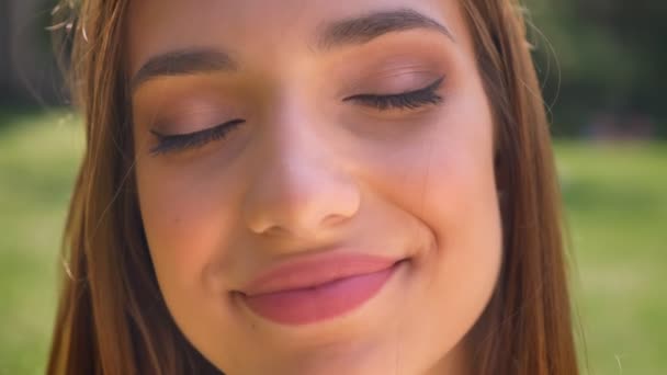 Rosto da mulher sexy fica com os olhos fechados, diversão conceito relógios na câmera, sorriso, fundo borrado — Vídeo de Stock