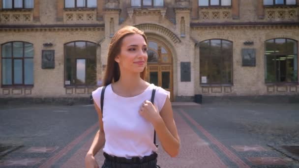 Belle jeune femme quitte l'université, se promène dans le parc en journée en été, vagues bonjour, concept de communication — Video