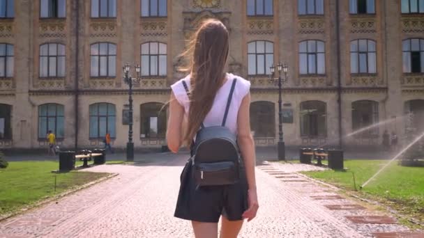 Silhouet van jonge vrouw wandelingen langs aan de Universiteit in park overdag in de zomer — Stockvideo