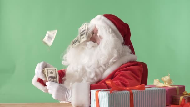 Zufriedener Weihnachtsmann wirft Geldscheine aus einem Bündel Geld auf den Tisch, Geldkonzept, im Hintergrund Chromakey. — Stockvideo