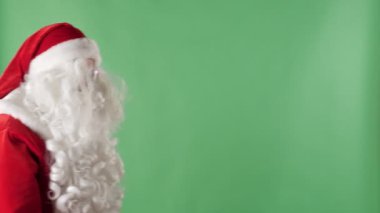 Noel Baba bir çanta ile çerçeve bak kamera ve onun elini sallayarak, arka planda jest yeşil chromakey tebrik girer.