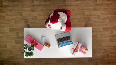 Noel Baba laptop, kulaklık, müzik dinleme ofisinde çalışan yazarak, havadan görünümü, atış üst metni bir not defterine yazar