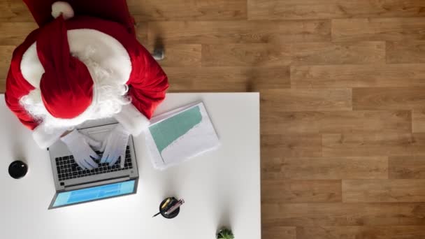 Άγιος Βασίλης εργάζεται σε γραφείο, σε laptop, δακτυλογράφηση, αεροφωτογραφία, πάνω προς τα κάτω shot, πυροβόλησε κουκλίτσα — Αρχείο Βίντεο