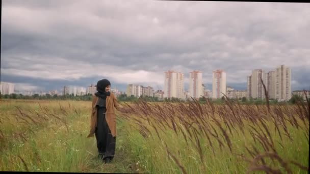 Unga muslimska kvinnan i hijab promenader genom vetefält och röra vid den med hennes hand, leende — Stockvideo