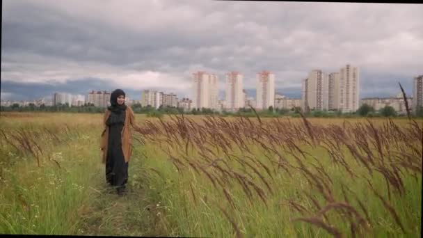 El ile yüksek çim alan yürürken ve onunla dokunmadan hijab içinde genç mutlu Müslüman kadın, gülümseyen — Stok video