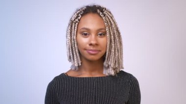 Gülümseyen ve kameraya bakarak dreadlocks ile genç Afrikalı kız, beyaz duvar arka plan.