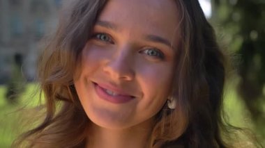 Bir parkta genç gülümseyen beyaz esmer, üniversite içinde belgili tanımlık geçmiş portresi