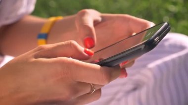 Kullanma smartphone, yazarak, swiping, güneşli bir gün, arka plan, yaz, kırmızı manikür yeşil doğa eller