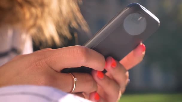 Mains féminines utilisant smartphone, dactylographie, balayage, journée ensoleillée, été, manucure rouge — Video