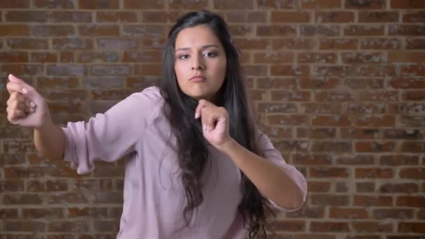 Vidám mulatto lány vidáman táncoló, tégla fal a háttérben — Stock videók