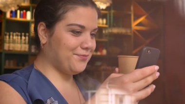 Onun pnone swiping ve kağıt bardak içki ile holding beyaz joly kız büyük boy