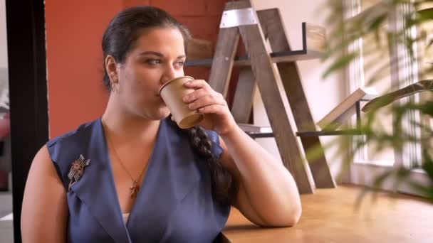 Gruesa chica caucásica bebiendo su café mirando en cámara con sonrisa — Vídeos de Stock