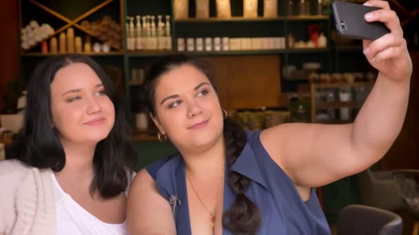 Duas garotas caucasianas ouffy tirar fotos deles no smartphone enquanto sentado no café — Vídeo de Stock