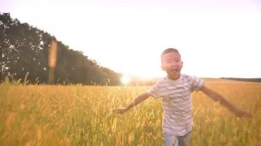 Güzel Asyalı mutlu çocuk çalıştırmak otların arasında sarı peyzaj çarpıcı