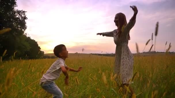 Felice madre asiatica saltando con il suo figlio carino su un bel campo in campagna — Video Stock