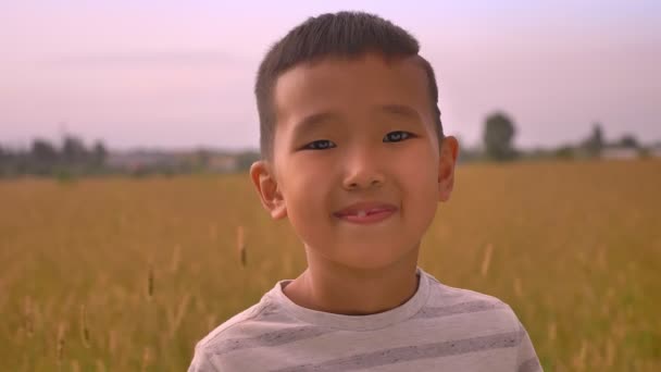 Молодой счастливый азиатский ребенок наслаждается закатом на пшеничном поле — стоковое видео
